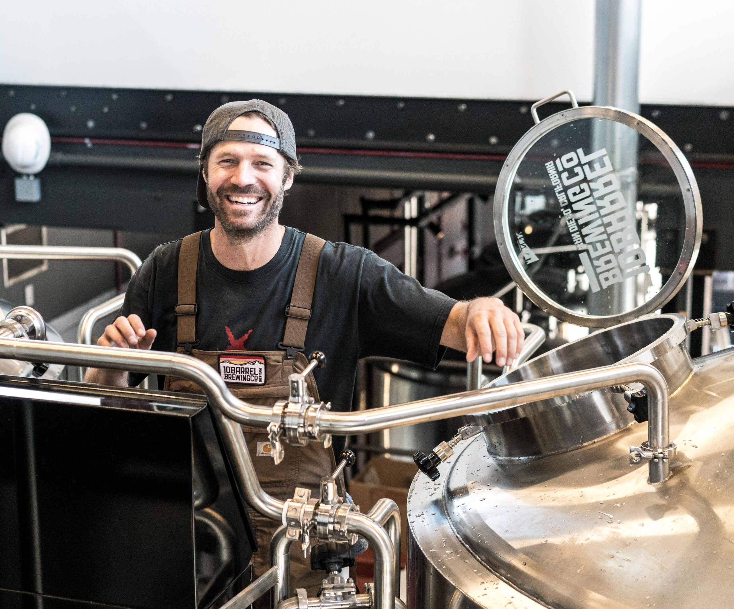 Man smiling standing behind brewing equipment
